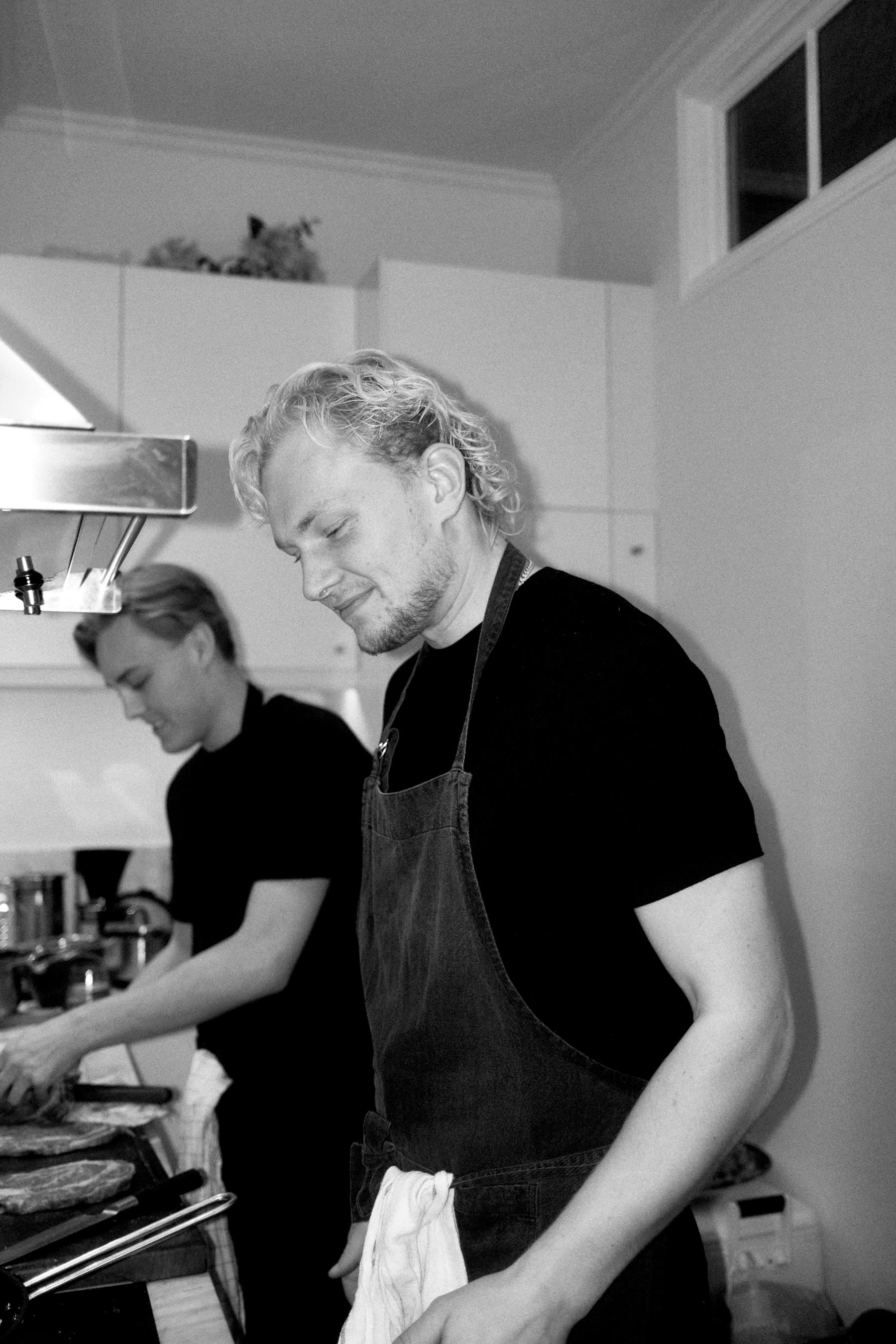 Two cooks in aprons working side by side in a home kitchen